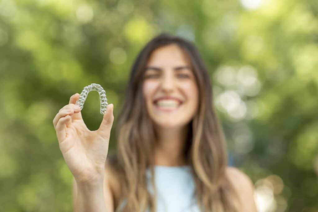 Girl holding Invisalign retainer at Farina Orthodontics